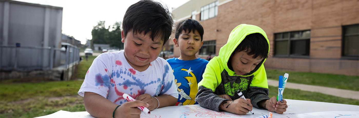 three students coloring outside