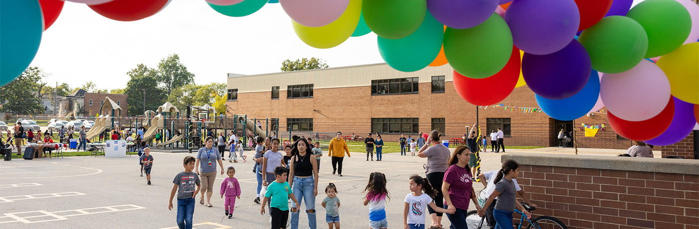 students and families walking under colorful balloon arch